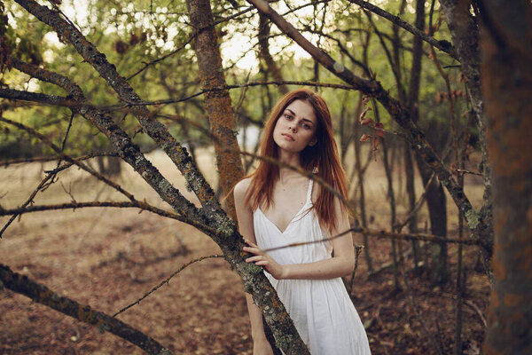 Pretty woman in white dress near tree posing in studio