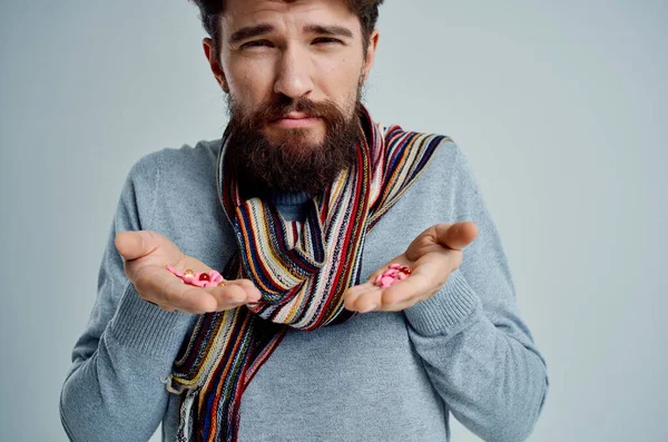 Hombre barbudo tratamiento de la enfermedad con pastillas en las manos fondo claro —  Fotos de Stock