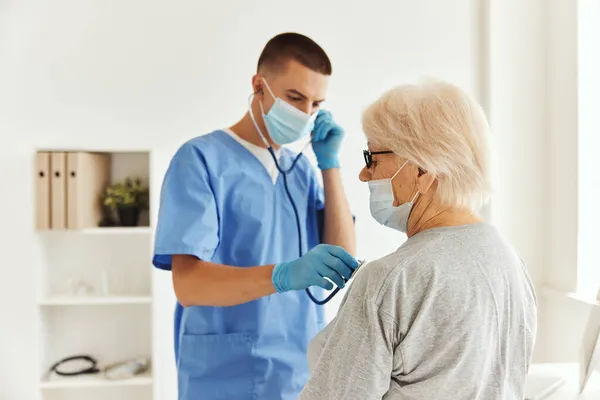 Medico in maschera medica esaminare un paziente assistenza sanitaria — Foto Stock