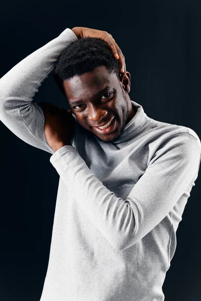 Allegro afroamericano in un maglione tiene la testa ritagliata vista sfondo scuro — Foto Stock