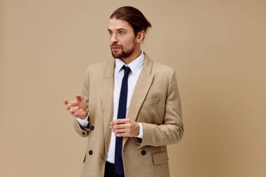 Bej ceketli bir adam şık bir moda tarzında soyutlanmış arka planda duruyor.