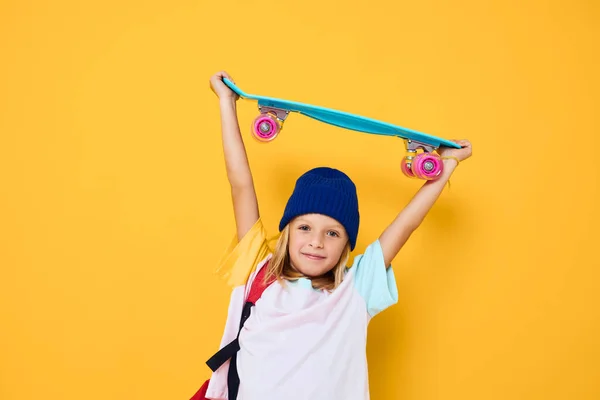 Foto av söt liten flicka i en vit t-shirt poserar med en skateboard i hand isolerad bakgrund — Stockfoto