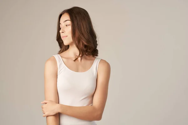 Vrolijk vrouw in een wit t-shirt haarverzorging licht achtergrond — Stockfoto