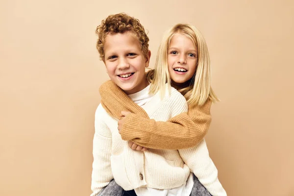 Kinder zusammen in Pullovern Spaß Freizeitkleidung beige Hintergrund — Stockfoto