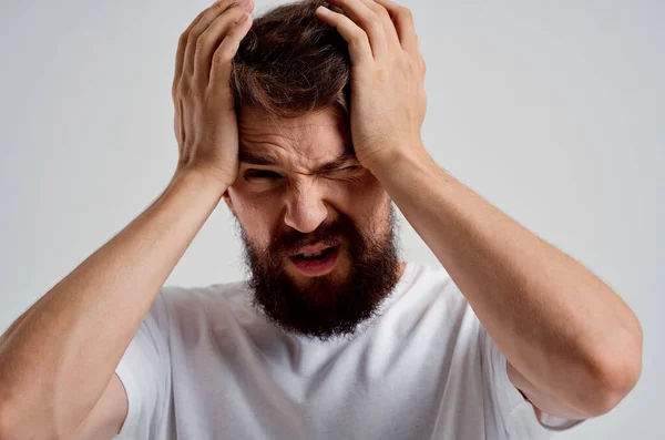 Emotionele man in een wit t-shirt hoofdpijn migraine problemen geïsoleerde achtergrond — Stockfoto