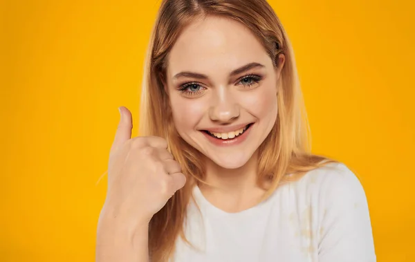 Весела красива блондинка в білій футболці посмішка емоції жовтий фон — стокове фото