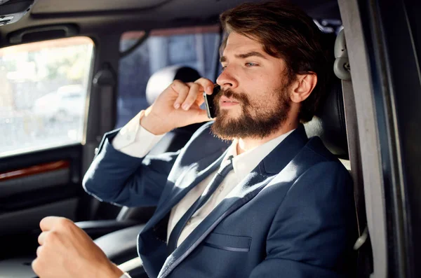 En man i kostym sitter i bilen och pratar i telefon. — Stockfoto