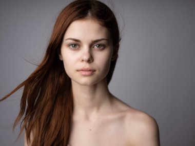 Güzel bir kadın, kızıl, çıplak omuzlar, izole edilmiş arka plan.