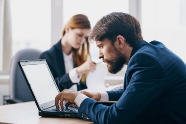 İş adamı ve kadın bir dizüstü bilgisayarın önünde oturuyor. İnternet teknolojileri.