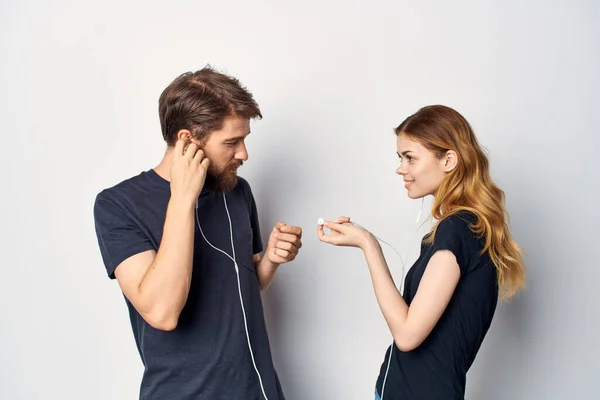Veselý mladý pár s telefonem v ruce emoce ve sluchátkách světlo pozadí — Stock fotografie