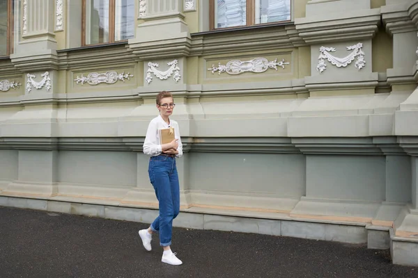 Gözlüklü güzel bir kadın kitap eğitimi alarak şehirde dolaşıyor.