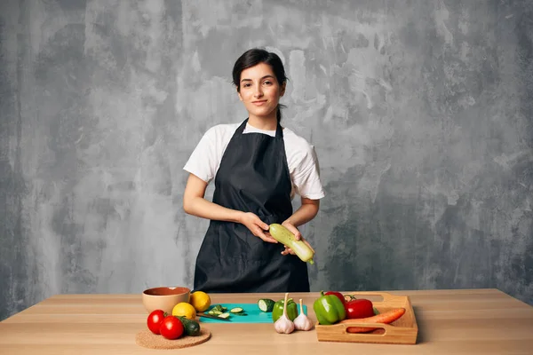 Mujer en la cocina en un delantal negro verduras cocina ensalada salud — Foto de Stock