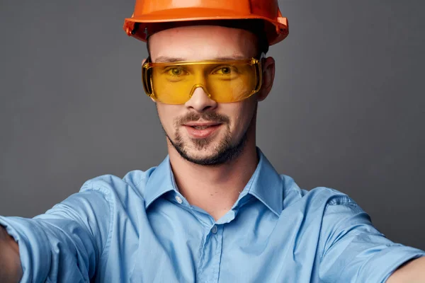 Homem em laranja chapéu duro design de construção camisa azul — Fotografia de Stock