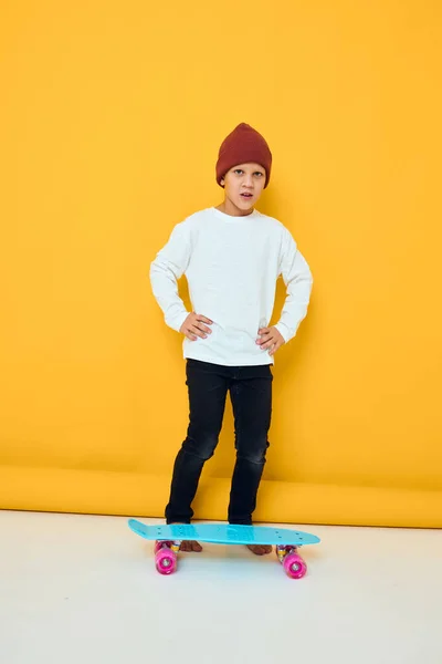 Rolig liten pojke i en röd hatt skateboard i händerna Barndom livsstil koncept — Stockfoto