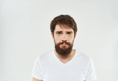 Beyaz tişörtlü adam ciddi görünüyor.