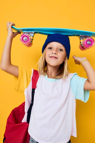 Snygg flicka med en skateboard på huvudet isolerad bakgrund — Stockfoto