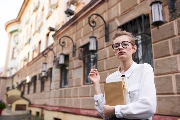 Student s brýlemi procházky po městě s knihou vzdělávání — Stock fotografie