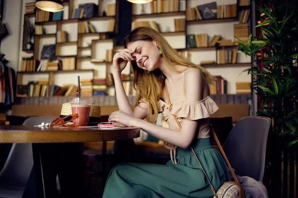 一个漂亮的女人坐在餐桌旁，在咖啡馆的交流中喝一杯 — 图库照片