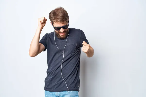 一个穿着黑色T恤 头戴耳机的英俊男人 在浅色背景下跳舞 高质量的照片 — 图库照片