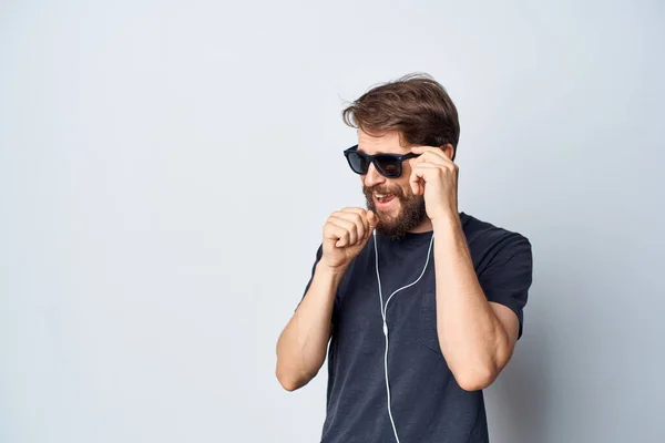 Man met baard in een zwart t-shirt muziek in hoofdtelefoon beweging geïsoleerde achtergrond — Stockfoto