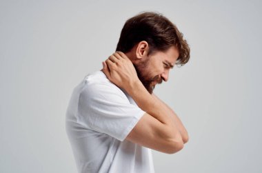 Beyaz tişörtlü bir adam. Boynunda ağrı kesici var. Arka planda izole edilmiş.