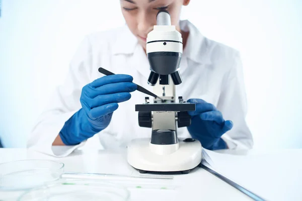 Asistente de laboratorio sentado a la mesa microscopio investigación luz fondo — Foto de Stock