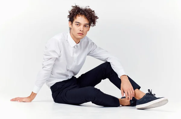 Chlap v bílé košili sedí na podlaze kudrnaté vlasy módy — Stock fotografie