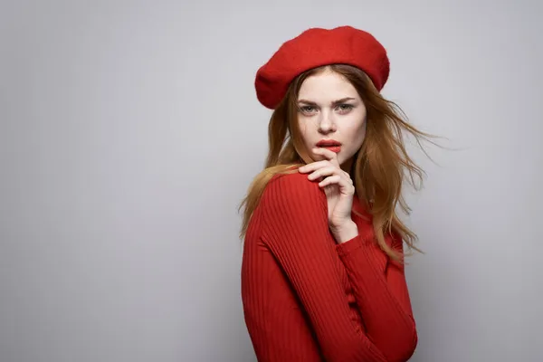 Bonita mujer con una gorra roja en la cabeza glamour fondo claro —  Fotos de Stock
