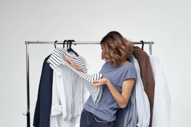 Elbise seçen güzel kadın kostüm ışığı arka planında.