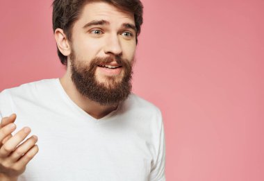 Beyaz tişörtlü sakallı adam hoşnutsuz görünüyor.