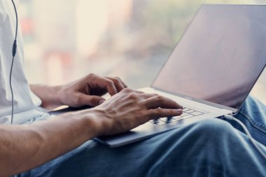 Sakallı adam pencere pervazında oturuyor.