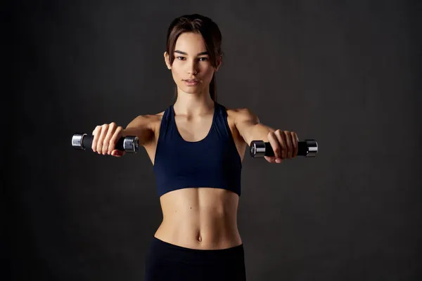 Güzel kadın fitness Koyu arkaplanın ellerinde dambıl egzersizi — Stok fotoğraf