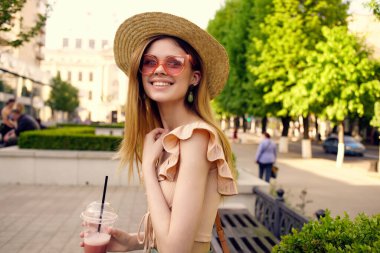 Güzel bir kadın parkta bir içkiyle yürüyor. Hayat tarzı.