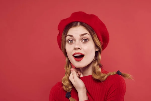 Fröhliche Frau mit roter Mütze auf dem Kopf glamouröser roter Hintergrund — Stockfoto