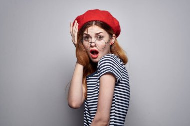 Çizgili tişörtlü güzel bir kadın. Kırmızı dudaklar. Elleriyle yaz jesti.