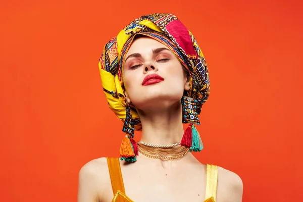 Glad kvinna i flerfärgad turban attraktiv utseende smycken röd bakgrund — Stockfoto