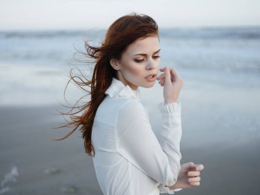 Beyaz elbiseli güzel, kızıl saçlı bir kadın. Yaşam tarzı, temiz hava moda seyahati.