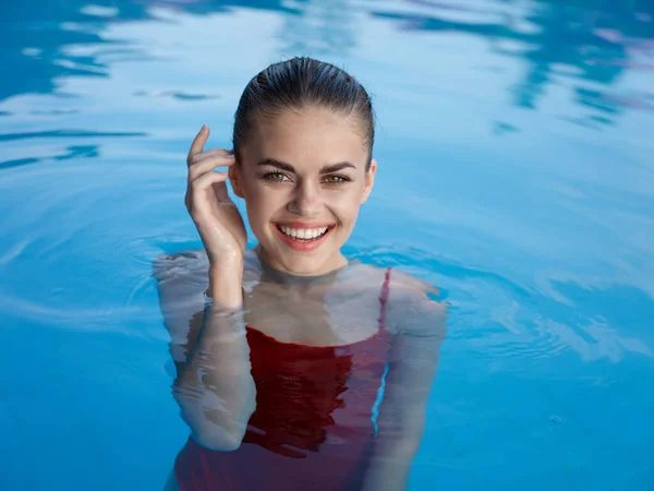 Веселая женщина в красном купальнике в бассейне улыбается роскошной моделью — стоковое фото