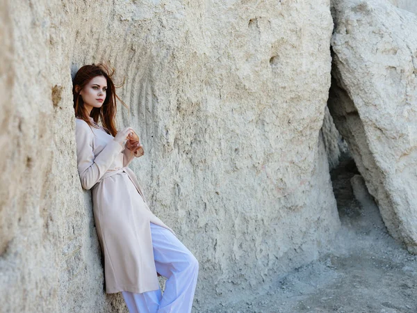 Femme posant près des rochers dans le sable style élégant — Photo