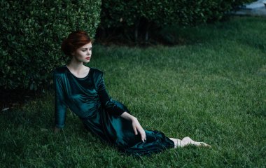 Yeşil elbiseli bir kadın bahçede yatar.