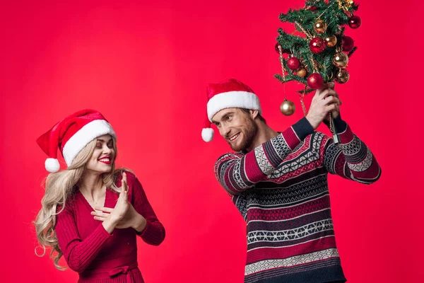 Man och kvinna med träd i händerna semester leksaker dekoration röd bakgrund — Stockfoto