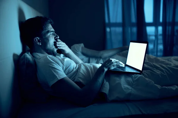 man at night in bed in front of laptop rest before bedtime