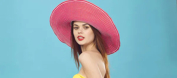 Romantisk kvinna i rosa hatt och gul baddräkt på blå bakgrund porträtt — Stockfoto