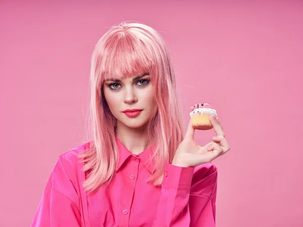 Mulher na camisa com bolo e penteado modelo de fundo rosa — Fotografia de Stock