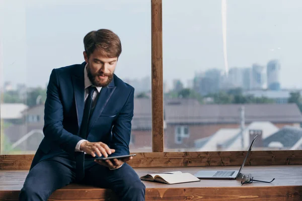 The man in a suit near the window with a laptop office