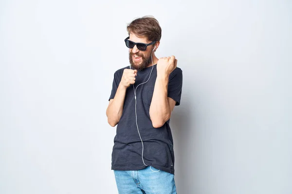 Γενειοφόρος άνθρωπος ακουστικά γυαλιά ηλίου μουσική χορό διασκέδαση φως φόντο — Φωτογραφία Αρχείου