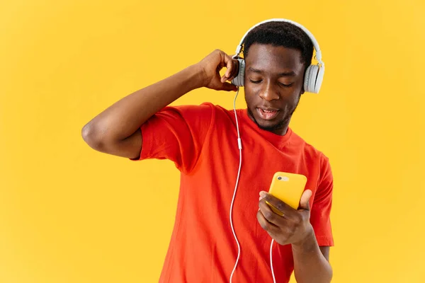 손에 전화기를 들고 음악 오락을 감상하고 있는 아프리카 계 미국인 — 스톡 사진