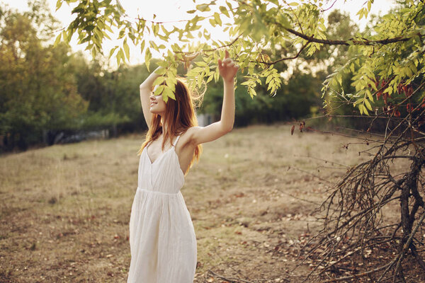 Cheerful woman in a white dress in the summer outdoors in the field. High quality photo