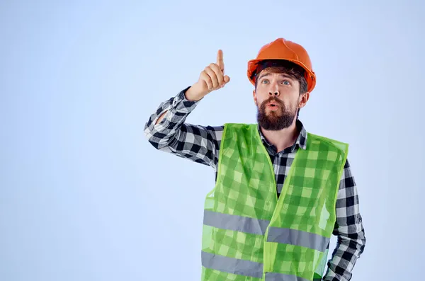 Homem trabalhador colete verde capacete laranja workflow mão gestos fundo azul — Fotografia de Stock