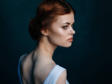 Beyaz elbiseli güzel bir kadın. Makyaj yüzü. Yakından poz veriyor.